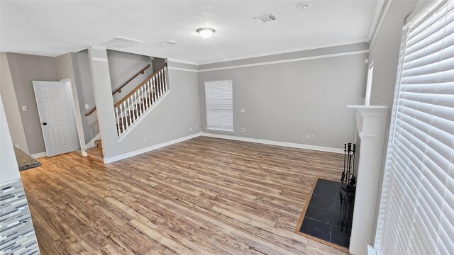 unfurnished living room featuring wood-type flooring and ornamental molding