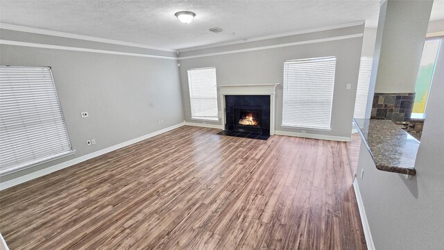 unfurnished living room featuring a textured ceiling, wood-type flooring, and crown molding