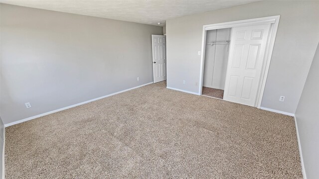 unfurnished bedroom featuring carpet floors, a textured ceiling, and a closet