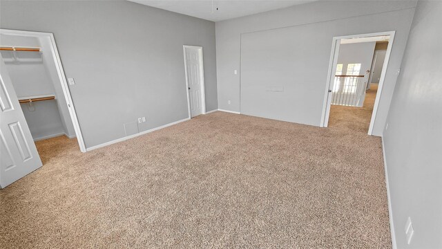 unfurnished bedroom with a walk in closet and light carpet