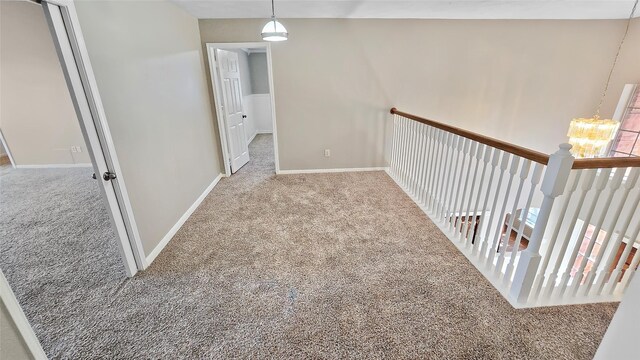 hall featuring carpet flooring and a chandelier