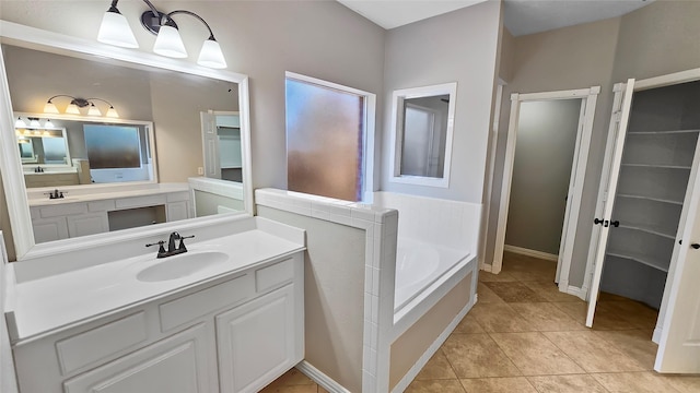 bathroom featuring tile patterned flooring, vanity, and a tub to relax in