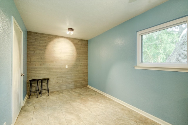 unfurnished room featuring wooden walls