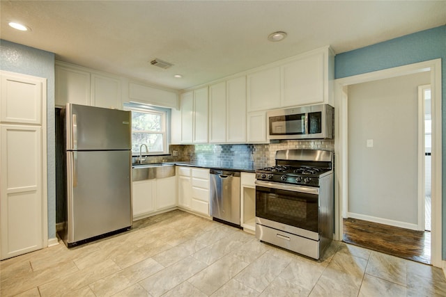 kitchen featuring sink, tasteful backsplash, light hardwood / wood-style floors, white cabinetry, and stainless steel appliances