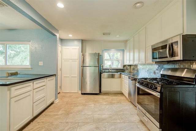 kitchen featuring appliances with stainless steel finishes, backsplash, white cabinetry, and sink