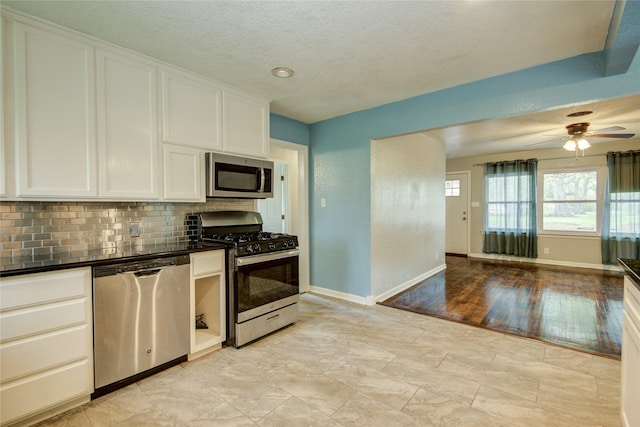 kitchen with white cabinets, light hardwood / wood-style flooring, ceiling fan, tasteful backsplash, and stainless steel appliances