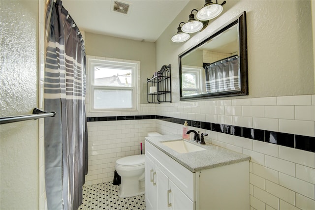 bathroom featuring a shower with shower curtain, vanity, tile walls, tile patterned flooring, and toilet