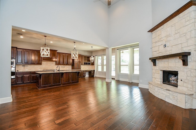 living room with a fireplace, dark hardwood / wood-style flooring, and a towering ceiling