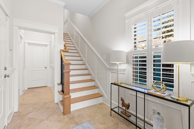 stairs with tile patterned floors and ornamental molding