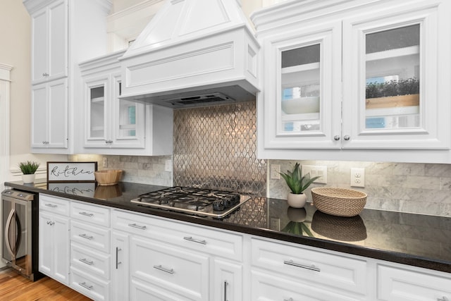 kitchen featuring stainless steel gas cooktop, backsplash, white cabinets, and custom exhaust hood