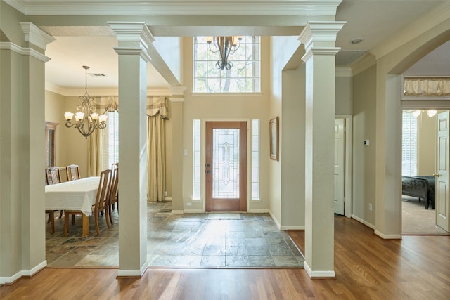 foyer with hardwood / wood-style flooring, ornamental molding, and a notable chandelier