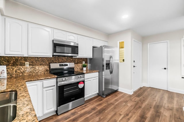 kitchen with white cabinets, stainless steel appliances, dark hardwood / wood-style floors, and dark stone countertops