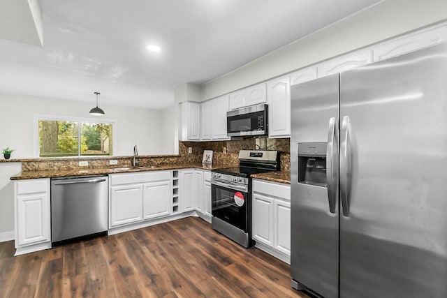 kitchen with dark wood-type flooring, hanging light fixtures, white cabinets, and stainless steel appliances