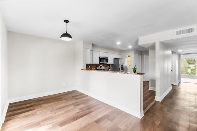 kitchen with light hardwood / wood-style floors, white cabinetry, kitchen peninsula, and stainless steel appliances