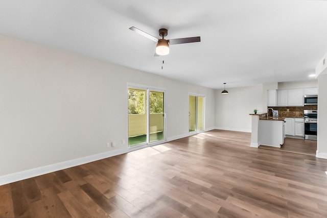 unfurnished living room featuring hardwood / wood-style flooring, ceiling fan, and sink