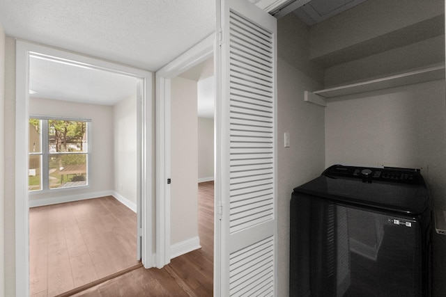 clothes washing area with hardwood / wood-style floors, a textured ceiling, and washer / clothes dryer