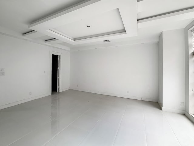 tiled empty room featuring a raised ceiling