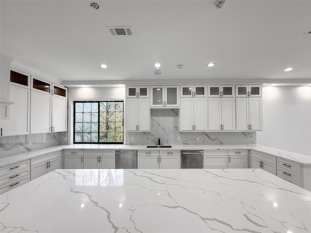 kitchen featuring sink, light stone counters, white cabinetry, and backsplash