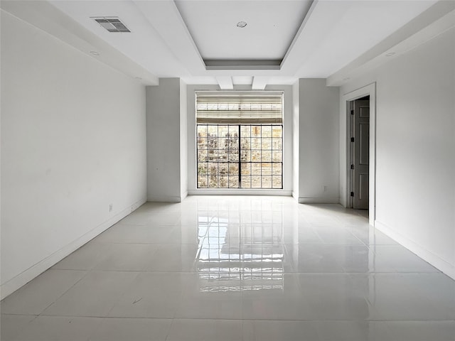 tiled spare room with a raised ceiling