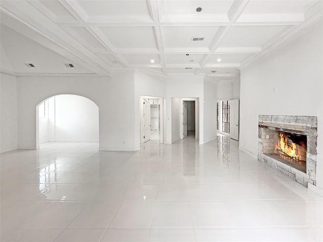 unfurnished living room featuring beam ceiling, a tile fireplace, coffered ceiling, light tile patterned floors, and ornamental molding