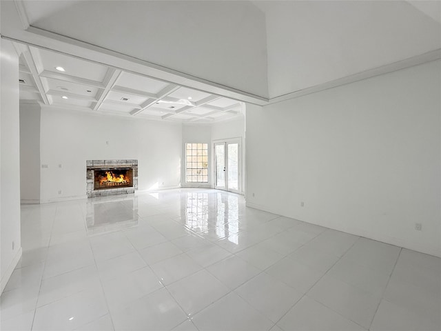 unfurnished living room with a fireplace, light tile patterned flooring, and coffered ceiling