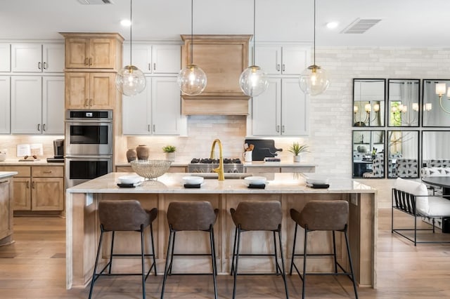 kitchen with white cabinets, appliances with stainless steel finishes, and a center island with sink