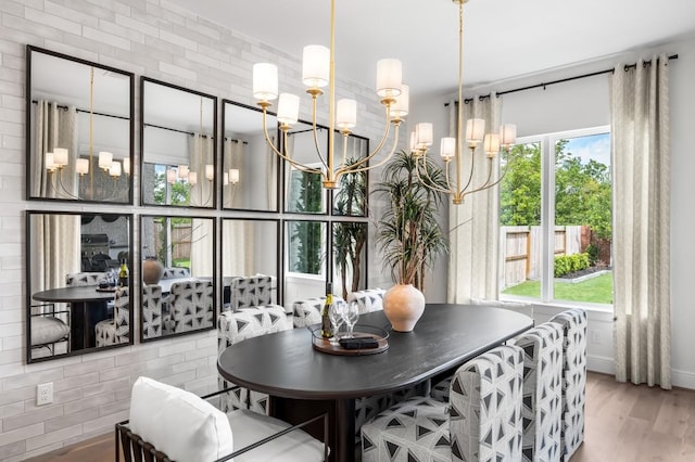 dining space with a wealth of natural light, wood-type flooring, and a notable chandelier