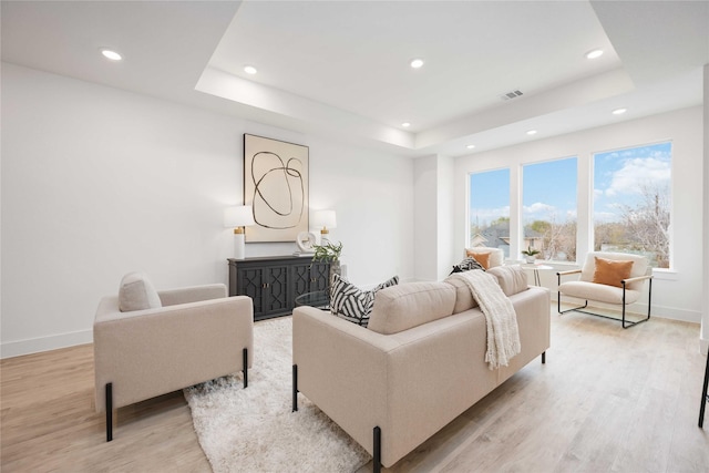 living room featuring light hardwood / wood-style floors and a tray ceiling