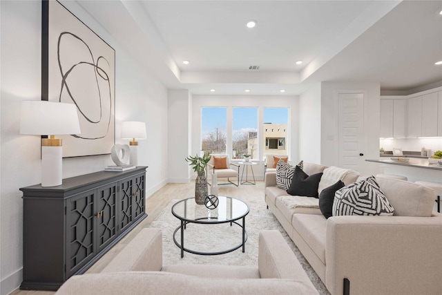 living room with a raised ceiling and light hardwood / wood-style flooring