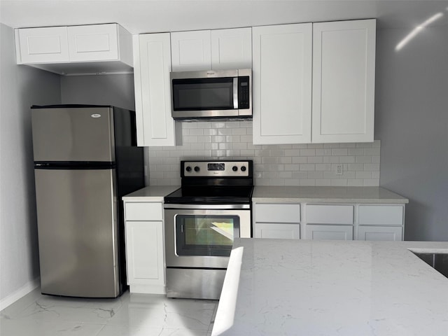 kitchen with backsplash, light stone counters, white cabinets, and stainless steel appliances