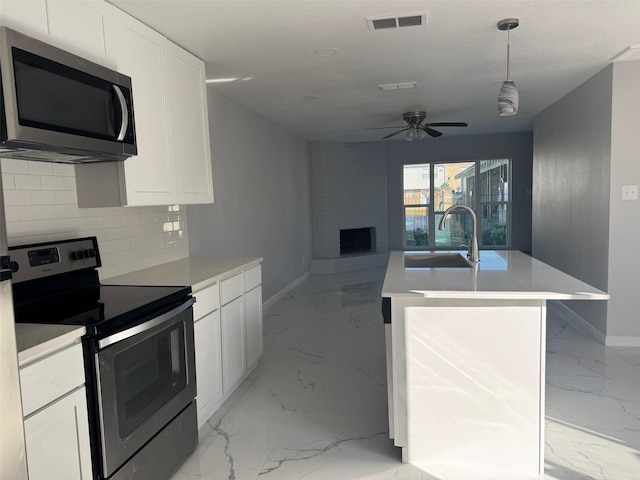 kitchen with ceiling fan, sink, stainless steel appliances, backsplash, and white cabinets