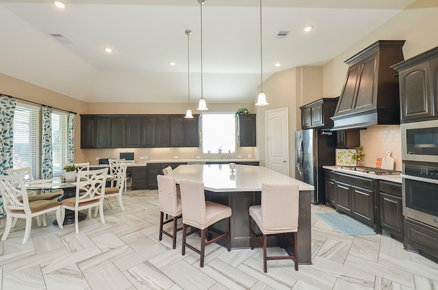 kitchen featuring tasteful backsplash, dark brown cabinetry, stainless steel appliances, a kitchen island, and hanging light fixtures