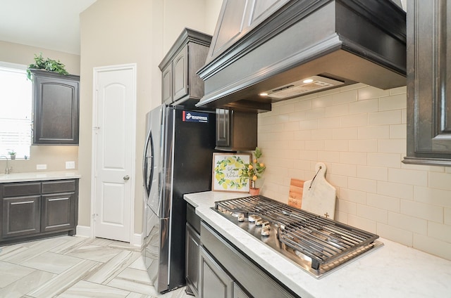 kitchen with decorative backsplash, custom range hood, and appliances with stainless steel finishes