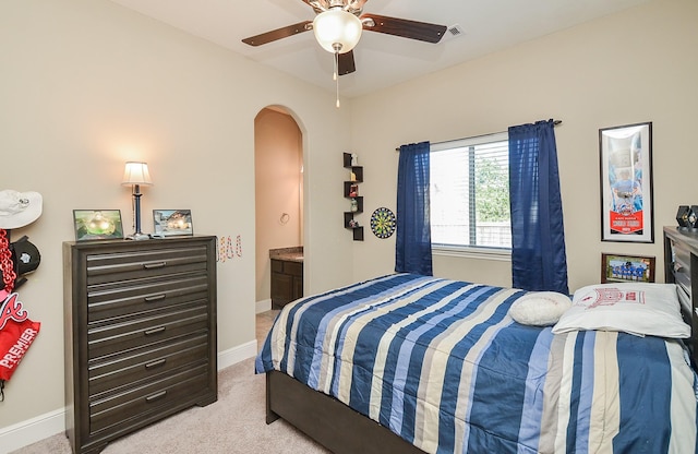 carpeted bedroom with ensuite bathroom and ceiling fan