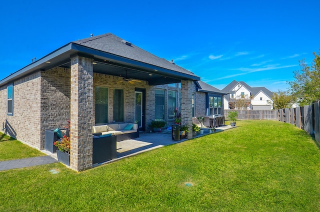 rear view of property with a lawn, ceiling fan, an outdoor living space, and a patio