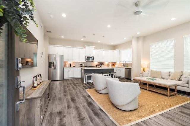 living room featuring hardwood / wood-style flooring, ceiling fan, and sink