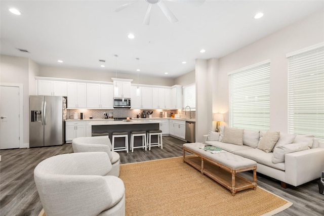 living room featuring dark hardwood / wood-style flooring, ceiling fan, and sink