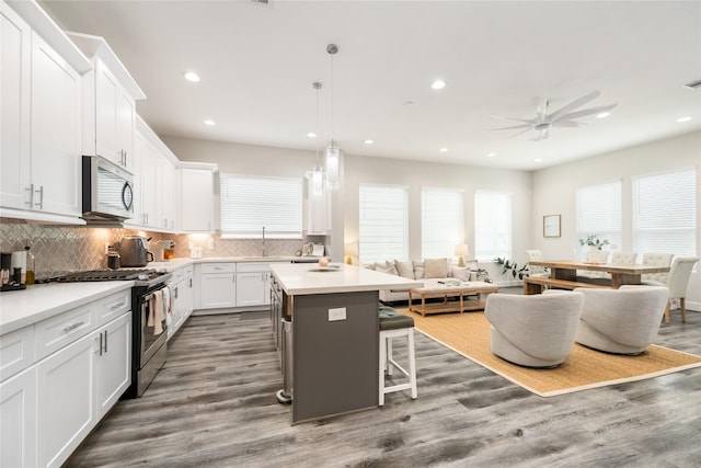 kitchen featuring a center island, stainless steel appliances, decorative light fixtures, a breakfast bar, and white cabinets