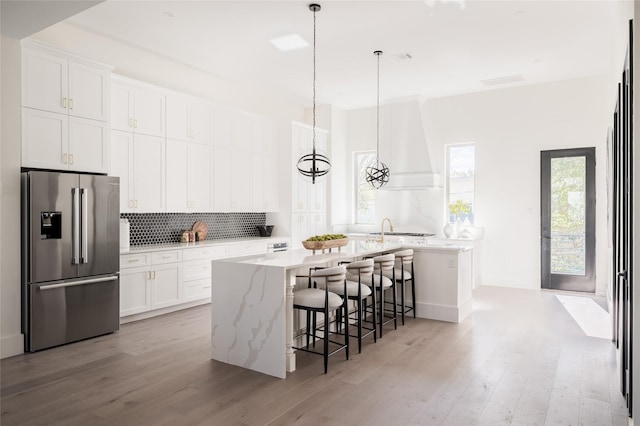 kitchen featuring white cabinets, stainless steel refrigerator with ice dispenser, and an island with sink