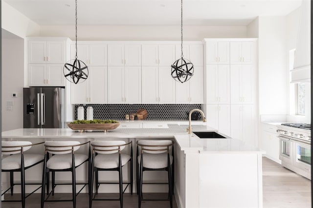 kitchen featuring a kitchen island with sink, sink, hanging light fixtures, and high end appliances