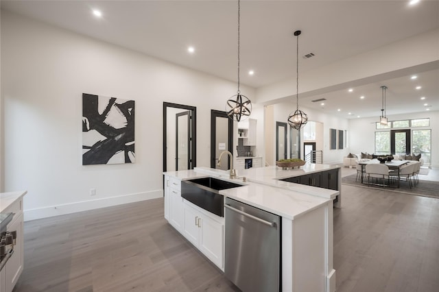 kitchen featuring sink, hanging light fixtures, stainless steel dishwasher, a spacious island, and white cabinets