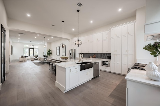 kitchen with white cabinets, appliances with stainless steel finishes, pendant lighting, and a spacious island