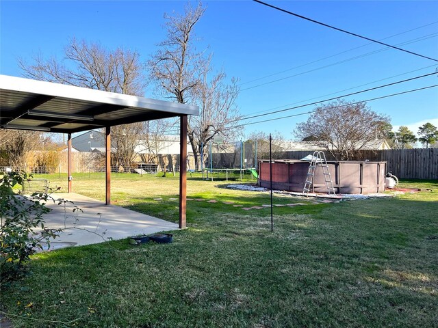 view of yard with a fenced in pool, a patio area, and a trampoline