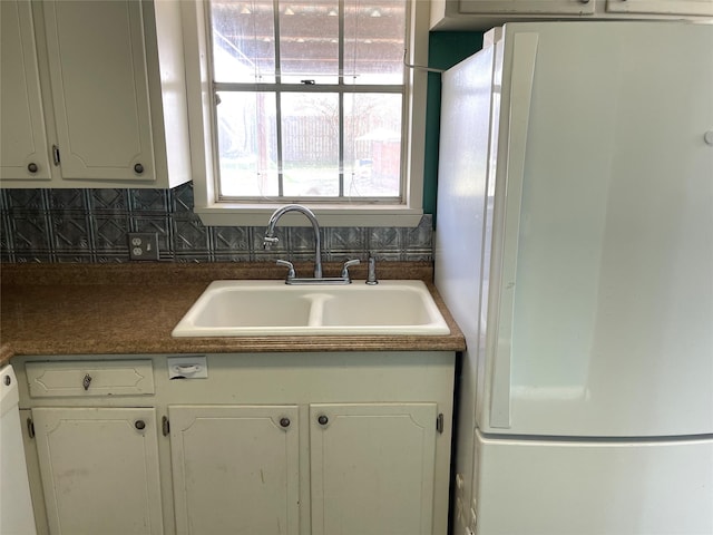 kitchen featuring decorative backsplash, white appliances, white cabinetry, and sink