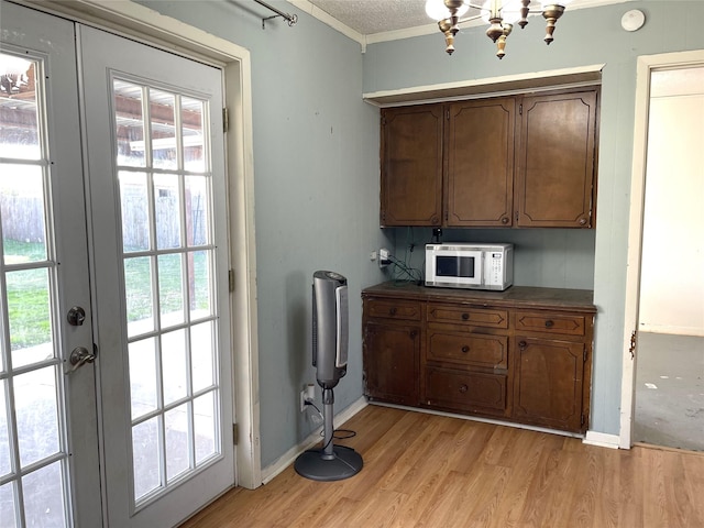 kitchen featuring french doors, a textured ceiling, light hardwood / wood-style flooring, and crown molding