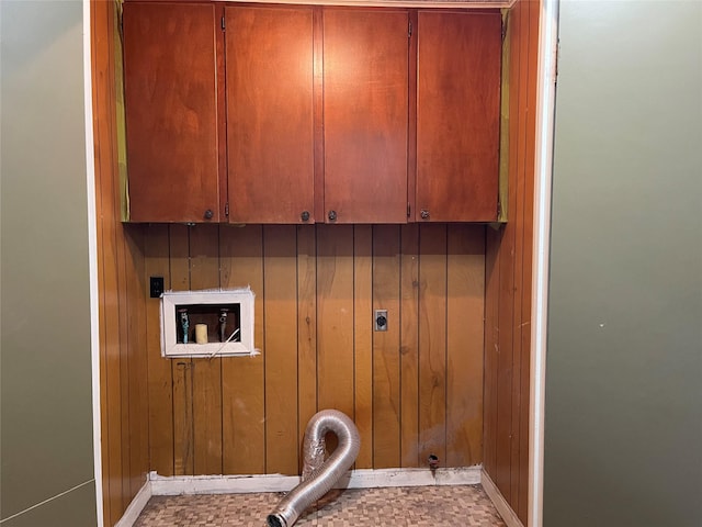 clothes washing area featuring cabinets, hookup for a washing machine, electric dryer hookup, and wood walls