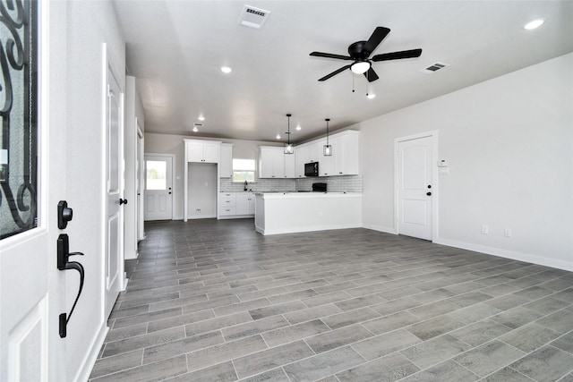 kitchen with kitchen peninsula, ceiling fan, pendant lighting, light hardwood / wood-style flooring, and white cabinetry