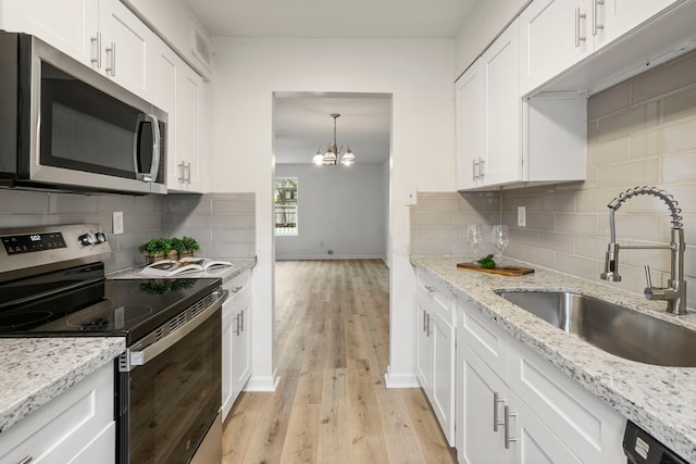 kitchen with appliances with stainless steel finishes, light hardwood / wood-style floors, white cabinetry, and sink