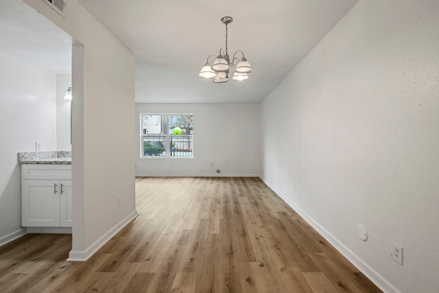 unfurnished dining area with light hardwood / wood-style flooring and a notable chandelier