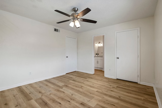 unfurnished bedroom with ceiling fan, ensuite bathroom, light hardwood / wood-style floors, and a textured ceiling